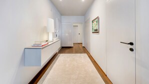 A hallway with a white wall, a wooden floor, a light-colored rug, a white door, and a framed picture on the wall. - Luxury Lakefront Loft in Montreux Swiss Reviera (Territet)