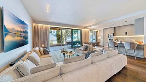 A modern living room with a large sofa, a dining area, and a kitchen. - Luxury Lakefront Loft in Montreux Swiss Reviera (Territet)