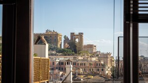 A view of a cityscape through a window, featuring historic buildings and a prominent tower. - Amazing Via del Tritone (Roma)