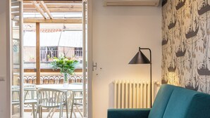 A room with a teal sofa, a dining table with chairs, a potted plant, and a radiator. - Amazing Via del Tritone (Roma)