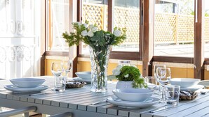 A dining table set with white plates, bowls, and glasses, a vase with white flowers, and a small plant. - Amazing Via del Tritone (Roma)
