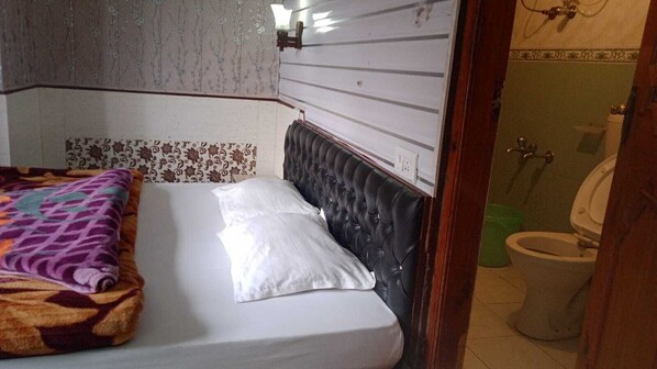 A room with a bed, a bathroom visible through an open door, and a patterned wall.