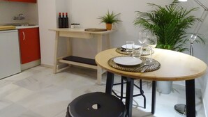 A compact kitchen with red cabinets, a small dining table set with plates, glasses, and a potted plant. - Arjona, modern and with excellent location (Sevilla)