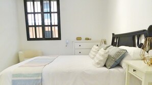 A bedroom with a bed, bedside tables, a nightstand, a window, and a wall-mounted shelf. - Arjona, modern and with excellent location (Sevilla)