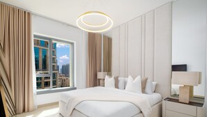 Et moderne hotelværelse med en stor seng, et fjernsyn, et vindue med gardiner, et sengebord med lampe og udsigt over bybilledet.