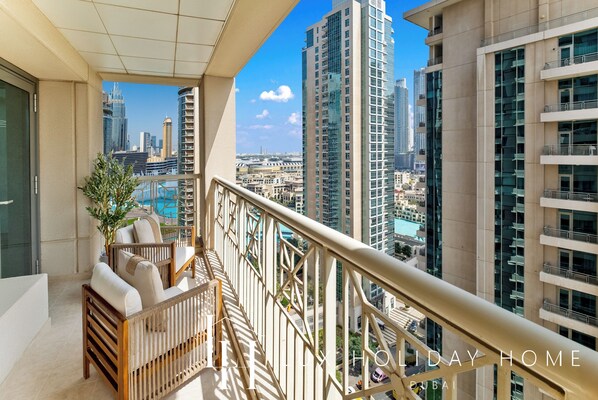 A balcony with a view of Dubai's skyline, including high-rise buildings and a pool.
