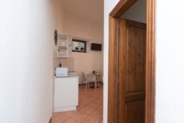 A hallway with a white refrigerator, a wooden door, and a tiled floor. - Jade 103 - Front of SMN Station - 2BR (Firenze)