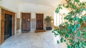 A spacious hallway with marble flooring, wooden doors, and a potted plant. - Jade 103 - Front of SMN Station - 2BR (Firenze)