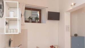 A modern hotel room with a white wall, a mounted TV, a small window with a view, a blue cabinet, and a white sink. - Jade 103 - Front of SMN Station - 2BR (Firenze)