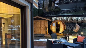 Puinen terassi ulkotiloineen, sauna ja vuoristomaisema taustalla.