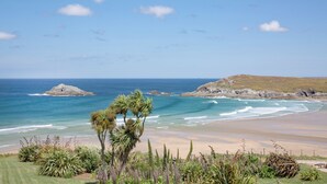 Un paisaje costero con playa, afloramientos rocosos y una zona cubierta de hierba y vegetación.
