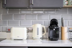 A kitchen counter with a Breville toaster, a Breville kettle, and a Tassimo coffee maker.