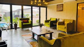 A modern interior with yellow sofas, a coffee table, and a view of the outdoors.