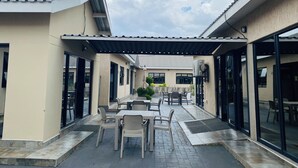 An outdoor patio with tables and chairs, a covered area, and a view of the sky.