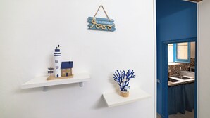 A room with a white wall, a blue door, and a kitchen area visible through the door.