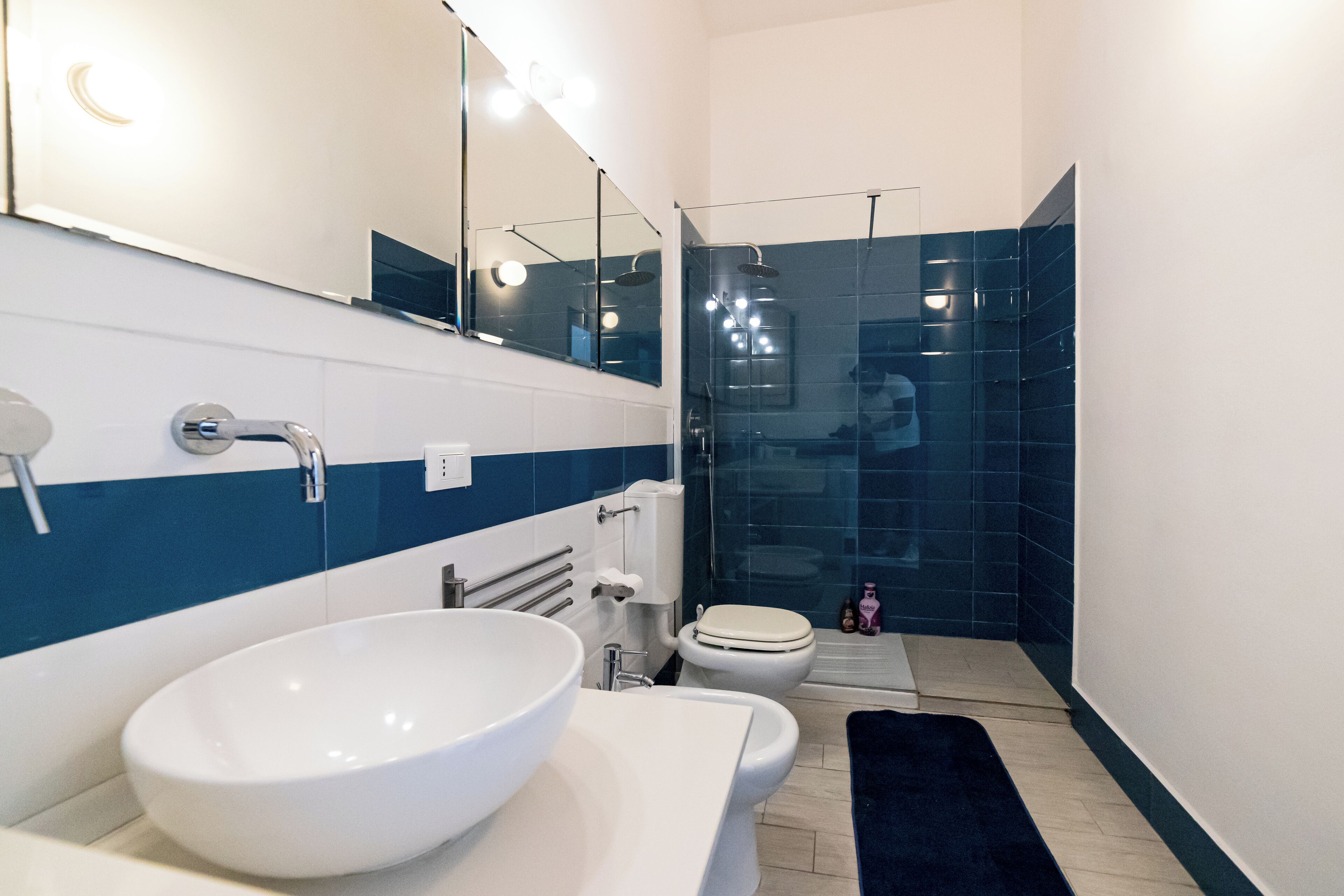 Un bagno moderno con un lavandino bianco ampio, un water e una cabina doccia in vetro.