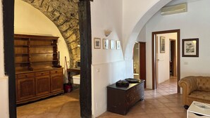 A spacious hallway with a stone archway, wooden furniture, and a tiled floor. - Agriturismo Contrada Guido (Sellia Marina)