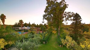 A well-maintained garden with a swimming pool, a white tent, and a pathway. - Agriturismo Contrada Guido (Sellia Marina)