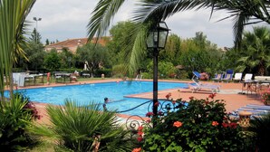 A swimming pool surrounded by palm trees and lounge chairs. - Agriturismo Contrada Guido (Sellia Marina)