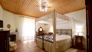 A four-poster canopy bed with a wooden headboard, a bedside table with a lamp, and a fireplace in the corner. - Agriturismo Contrada Guido (Sellia Marina)