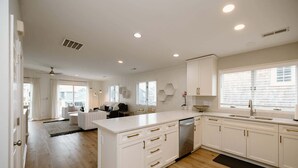 Una cocina moderna con armarios blancos, una isla central y un lavavajillas.