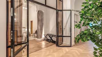 A modern interior with a herringbone wood floor, glass doors, and a large plant.