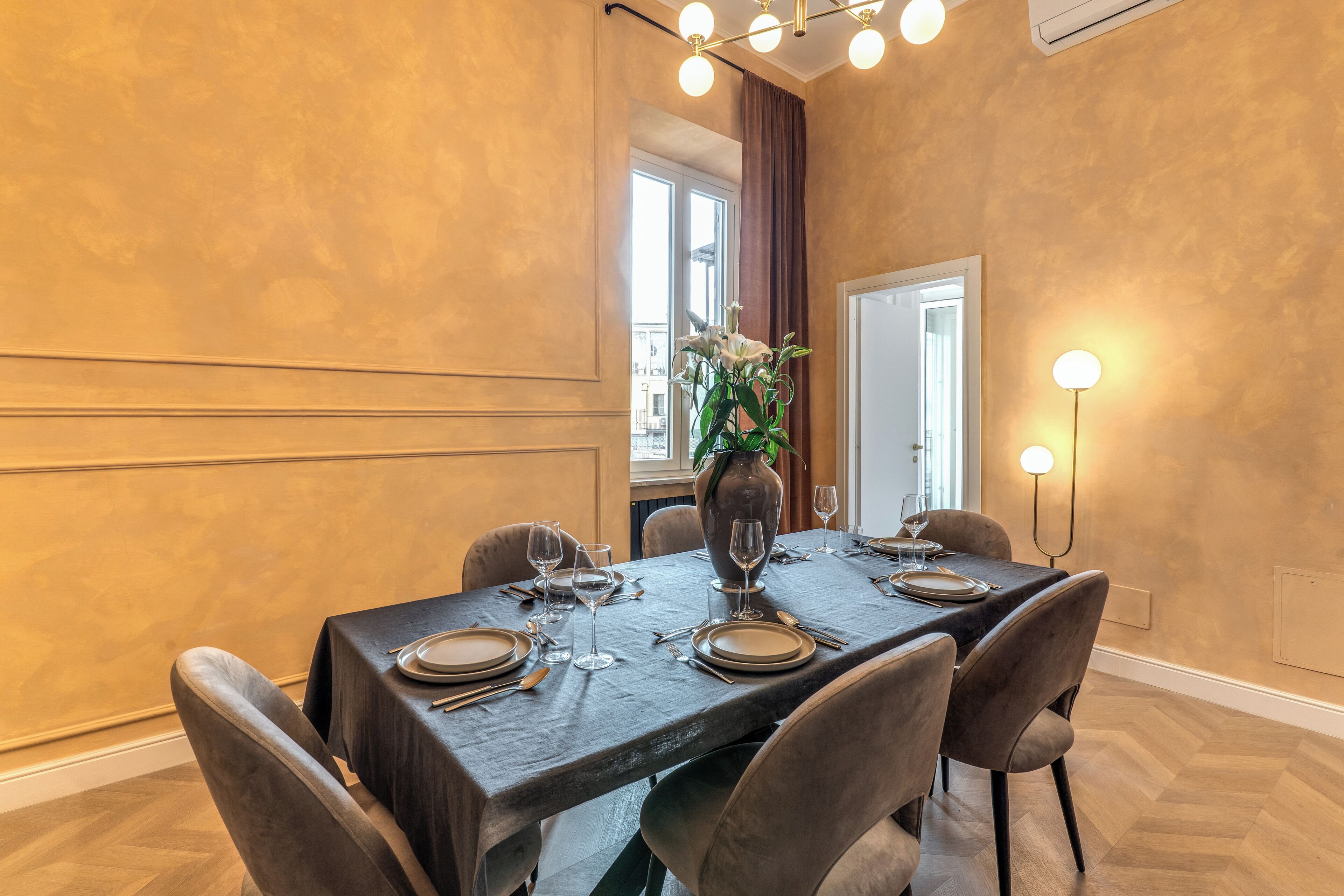 A dining area with a dark wooden table set for four, surrounded by upholstered chairs.