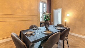 A dining area with a dark wooden table set for four, surrounded by upholstered chairs.