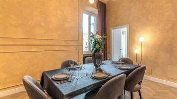 A dining area with a dark wooden table set for four, surrounded by upholstered chairs.