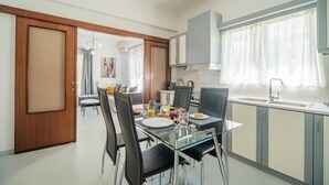 A modern kitchen with a dining area, featuring a glass table, black chairs, and a kitchen island. - THE NEST OF URBAN LIVING by 8essentially (Chania)