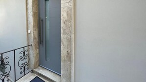 A door with a glass panel and a metal frame, set in a stone wall with a metal railing to the left. - THE NEST OF URBAN LIVING by 8essentially (Chania)