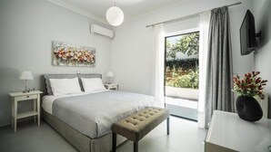 A bedroom with a bed, bedside tables, a bench, a TV, and a view of the outdoors. - THE NEST OF URBAN LIVING by 8essentially (Chania)