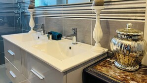 A modern bathroom with a large white sink, chrome fixtures, and a decorative vase on a marble countertop. - Le "33" Gîte de Charme coeur Cotentin (Valognes)