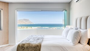 A bedroom with a large bed, a view of the ocean, and a mountain in the distance. - Clifton 2bed Penthouse Sea Views Dunmore Horizons (Cape Town)