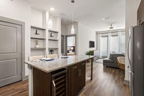 Une cuisine moderne dotée d’un plan de travail en granit, de meubles en bois et de luminaires suspendus.