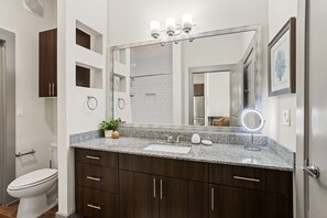 A modern bathroom with a granite countertop, a large mirror, and a toilet. - White Rock Lakewood Hideaway Pet-friendly Pool (Dallas)