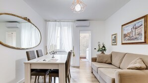 En moderne stue med spiseplads, der indeholder et træbord, stole, en beige sofa og et stort spejl.