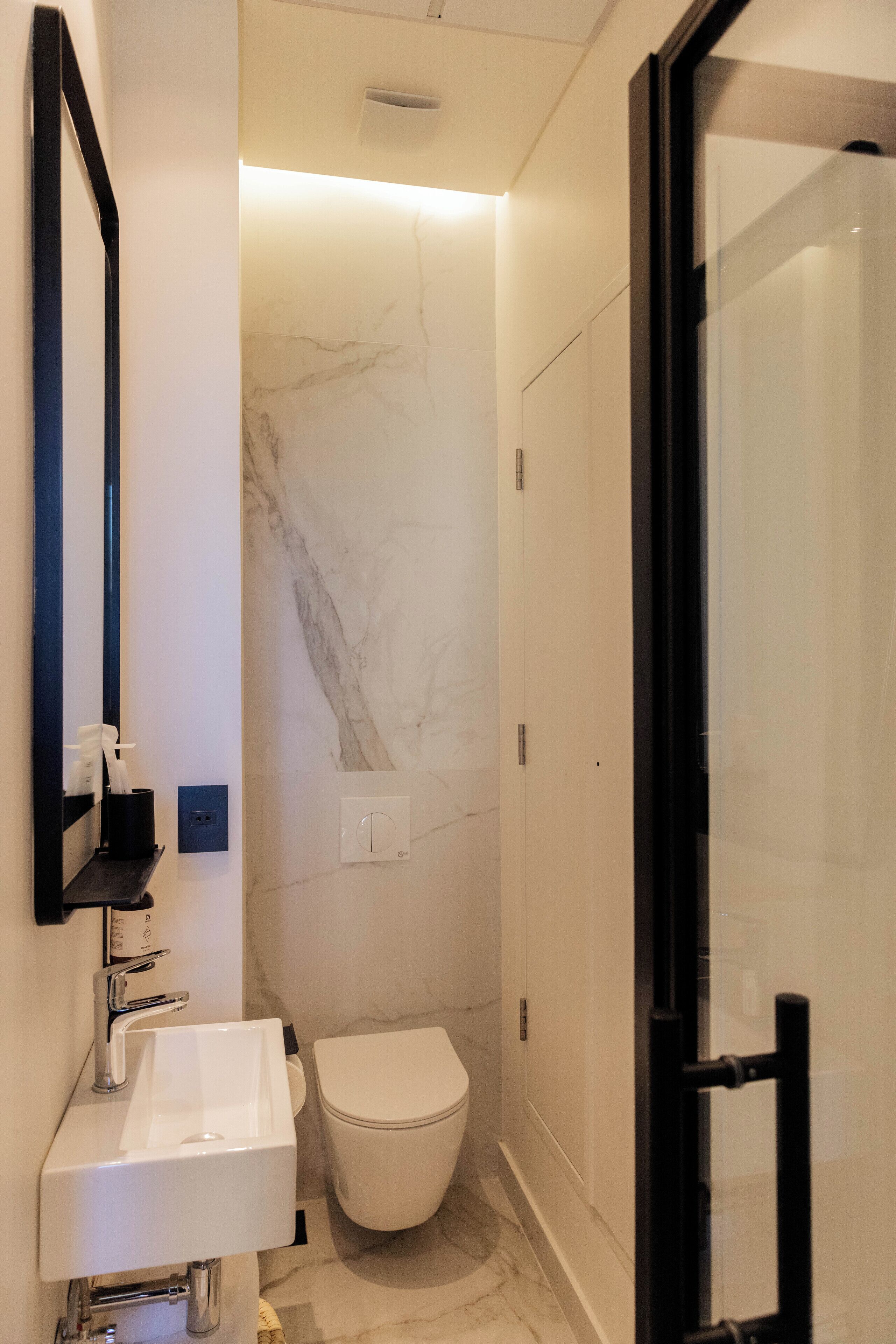 Un baño moderno con lavamanos blanco, inodoro y cabina de ducha de vidrio.