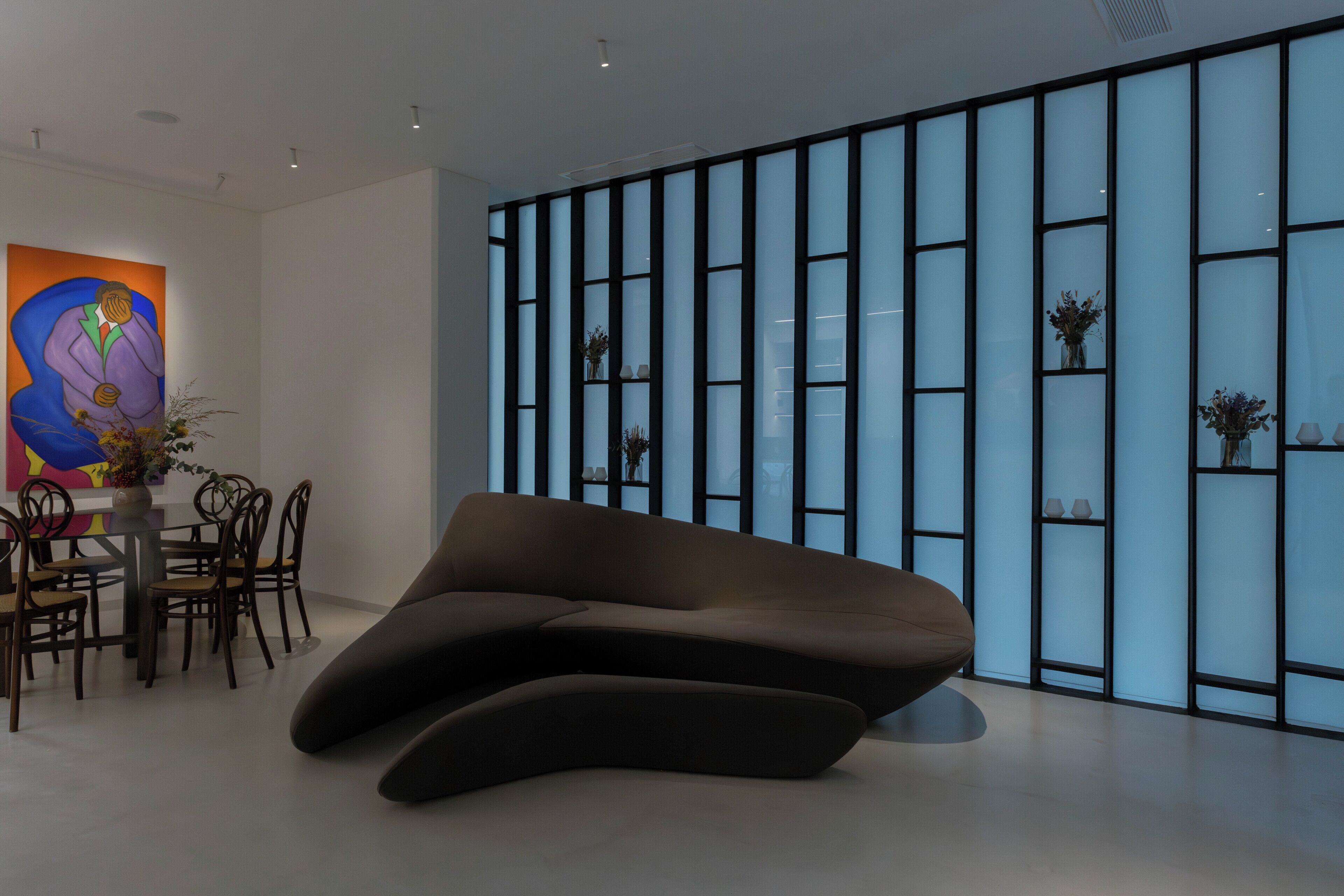 Un interior moderno con una zona de estar original, una mesa de comedor con sillas y una pared decorativa con estanterías.