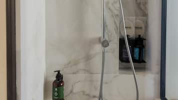 Une salle de bain moderne avec un mur en marbre, une douchette à main et une bouteille de shampoing.