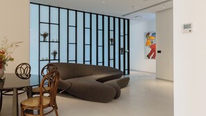 Un interno moderno con un divano componibile, un tavolo da pranzo con sedie e una parete decorativa con mensole.