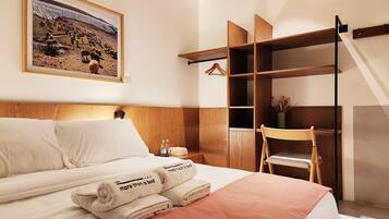 Une chambre d’hôtel avec un lit, une armoire en bois, un tableau au mur et une chaise.