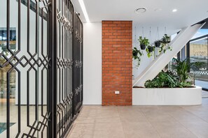 A modern interior with a brick wall, a staircase, and hanging plants.