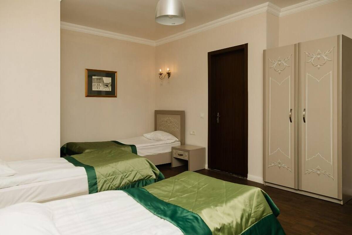 Une chambre d’hôtel avec deux lits simples, une table de chevet, une armoire et un tableau encadré au mur.