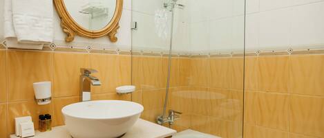 Un baño con un lavamanos ovalado grande, un espejo, una ducha y una bañera.