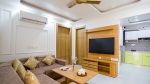 Un salon moderne avec un canapé, une table basse, un téléviseur et des meubles en bois.