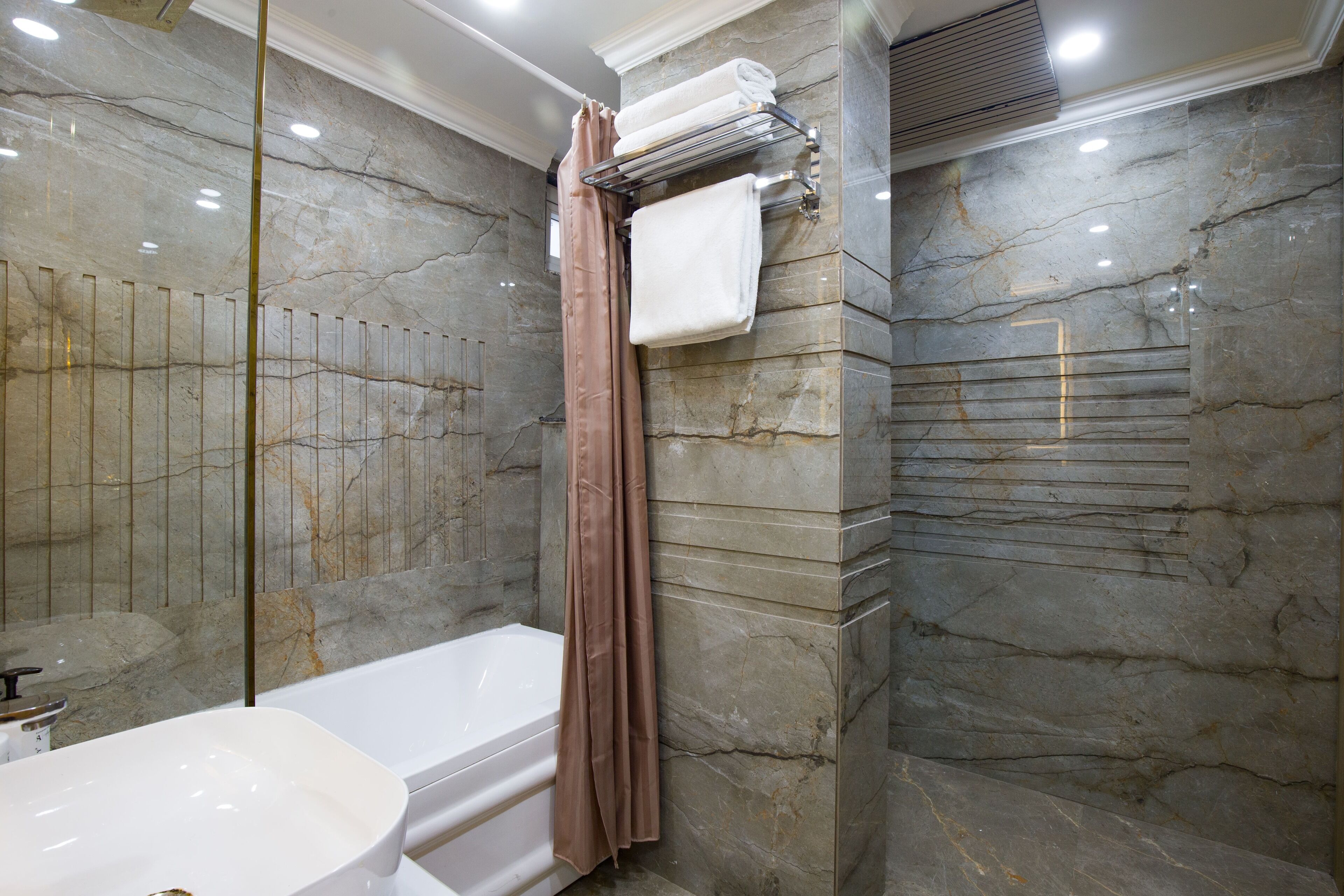 Un baño moderno con bañera, cabina de ducha de vidrio y paredes de mármol.