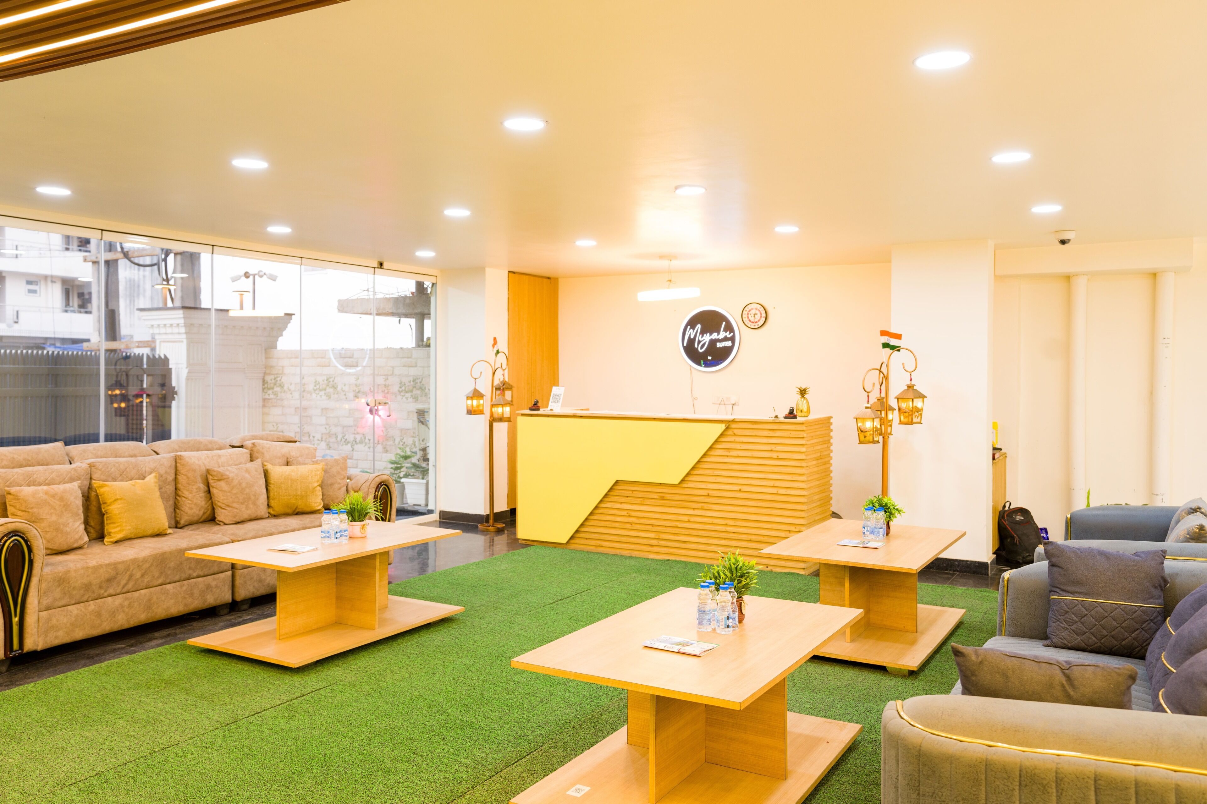 A hotel lobby with a reception desk, sofas, and tables.