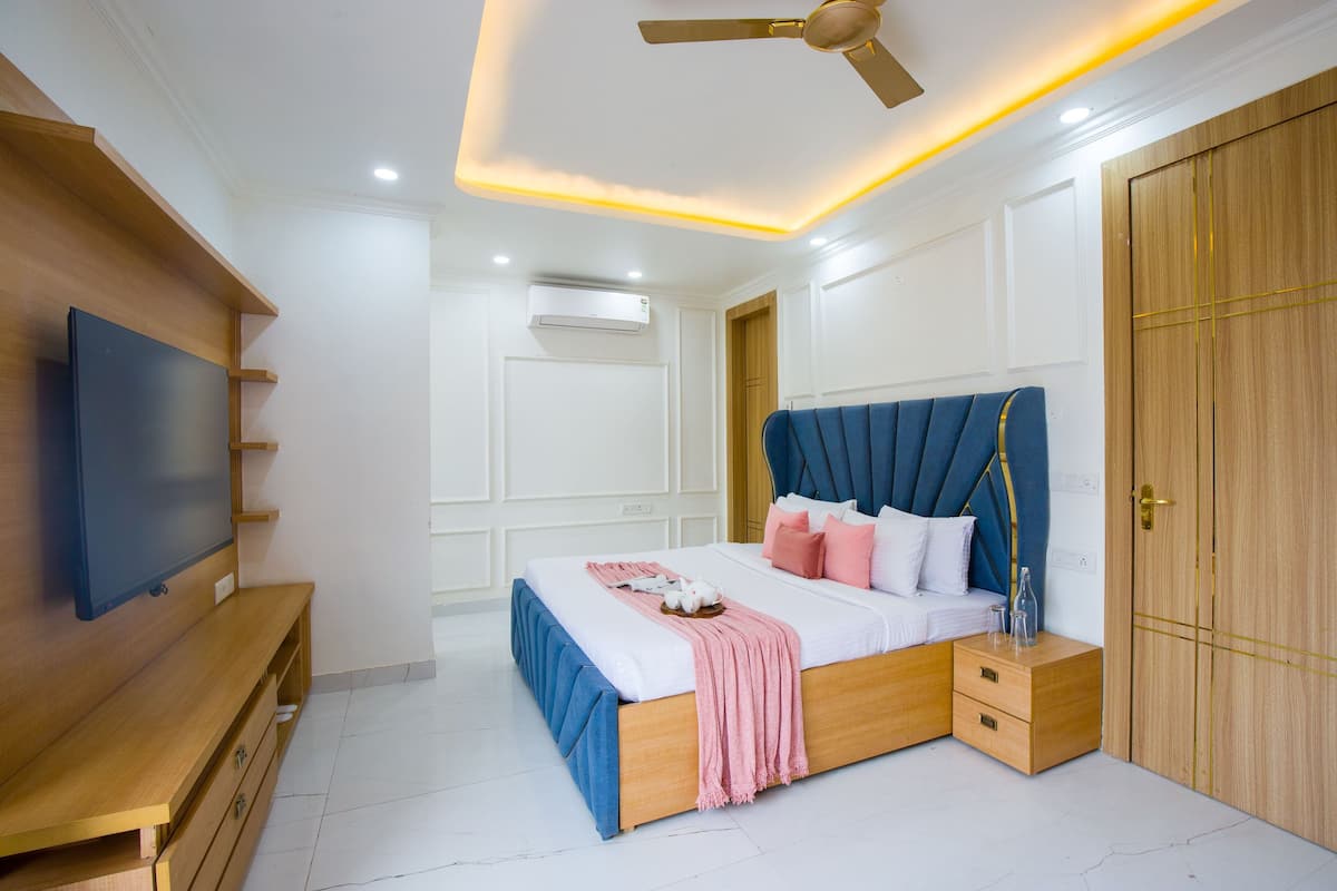 Een slaapkamer met een bed, nachtkastjes, een kledingkast en een tv op een houten dressoir.