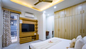 Une chambre d’hôtel dotée d’un grand lit, d’une armoire en bois, d’un téléviseur intégré et d’un balcon avec une porte coulissante.